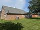 The home's brick exterior and a view of the green, grassy backyard at 5707 Sustar Dr, Monroe, NC 28110