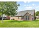 Manicured backyard lawn with a brick house, windows, and an air conditioning unit at 5707 Sustar Dr, Monroe, NC 28110