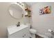 Stylish half bathroom featuring a modern vanity, round mirror, and decorative wall shelves at 6215 Cross Creek Ln, Charlotte, NC 28212