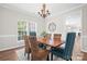 Elegant dining room featuring a wood table, wicker chairs, a chandelier, and natural light from the windows at 6803 Augustine Way, Charlotte, NC 28270
