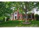 Traditional brick home featuring a well-manicured lawn and mature tree shading the facade at 6803 Augustine Way, Charlotte, NC 28270
