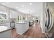 Open kitchen boasts white cabinetry, stainless steel appliances, an island, and a view into the inviting living area at 6803 Augustine Way, Charlotte, NC 28270
