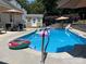 Inviting backyard pool with sun umbrellas, outdoor shed, patio seating, and a variety of fun inflatables at 7700 Antique Cir, Waxhaw, NC 28173