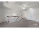 Spacious loft featuring neutral carpeting and railing with wood trim and an overhead ceiling fan at 858 Rook Rd, Charlotte, NC 28216