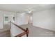 Neutral carpeted loft featuring an overhead ceiling fan, white walls, and a railing with wood trim at 858 Rook Rd, Charlotte, NC 28216