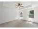 Bright main bedroom with neutral carpet, tray ceiling with overhead fan, and natural light from two windows at 858 Rook Rd, Charlotte, NC 28216