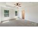 Main bedroom boasts natural lighting from two large windows, an overhead ceiling fan, and neutral carpet at 858 Rook Rd, Charlotte, NC 28216