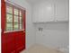 Laundry room with a red exterior door, white cabinets and tile flooring at 906 Wishing Well Ln, Charlotte, NC 28270