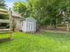 View of a lush, grassy yard with a shed, wooden playset, garden, and partially fenced perimeter at 9908 Park Springs Ct, Charlotte, NC 28210