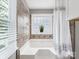 Beautiful bathroom featuring a tub with tile surround, shower curtain, and a glass block window at 9908 Park Springs Ct, Charlotte, NC 28210