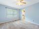 Light blue bedroom with ceiling fan, large window, carpet floors, and bathroom entrance at 9908 Park Springs Ct, Charlotte, NC 28210