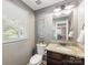 Charming powder room features granite countertop, decorative mirror, and natural light from the window at 9908 Park Springs Ct, Charlotte, NC 28210
