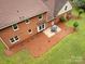 An angled aerial view of the brick home with an outdoor patio dining set at 113 Foxfield Ln, Matthews, NC 28105