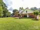 Spacious backyard with a well-manicured lawn, brick home, and mature trees at 113 Foxfield Ln, Matthews, NC 28105