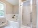 A well lit bathroom with a soaking tub under a window and a glass door shower at 113 Foxfield Ln, Matthews, NC 28105