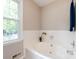 A well lit bathroom with a soaking tub under a window, blue hand towel, and potted orchid at 113 Foxfield Ln, Matthews, NC 28105