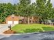 Charming brick home with lush front lawn, two car garage, and mature trees shading the front at 113 Foxfield Ln, Matthews, NC 28105
