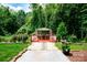 Landscaped backyard featuring a gazebo with chairs and a table surrounded by beautiful trees at 1548 Logan Patrick Ct, Gastonia, NC 28052