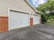 Two-car garage exterior featuring white doors, brick accents, and landscaping at 17136 Red Feather Dr, Charlotte, NC 28277