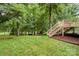 Lush green backyard featuring a wooden deck, with stairs leading to the yard at 172 Hunters Hill Dr, Statesville, NC 28677