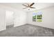 Well-lit bedroom featuring a ceiling fan, plush carpet, and a window overlooking a green lawn and bright sky at 174 Bellingshire Dr, Mt Ulla, NC 28125