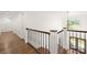 Second floor hallway with wood floors, wrought iron railings, and a view of the foyer chandelier at 174 Bellingshire Dr, Mt Ulla, NC 28125