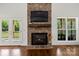 Living room with stone fireplace, TV, mantel, hardwood floors, and French doors to the outside at 174 Bellingshire Dr, Mt Ulla, NC 28125