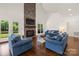 Living room with stone fireplace, TV, mantel, hardwood floors, blue furniture and lots of natural light at 174 Bellingshire Dr, Mt Ulla, NC 28125