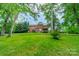 View of the back of the home featuring lush trees and an expansive lawn at 2004 Viscount Dr, Matthews, NC 28104