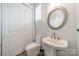 A well-lit powder room features a pedestal sink, a round mirror, and shaker-style doors at 2004 Viscount Dr, Matthews, NC 28104