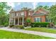 Charming brick home featuring a covered front porch with white columns and professionally landscaped yard at 2004 Viscount Dr, Matthews, NC 28104
