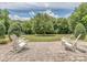 Backyard with a brick patio, two white Adirondack chairs and a large grassy area at 314 Candella Dr, Matthews, NC 28104