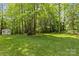 Expansive backyard with lush green lawn and mature trees plus an outbuilding for storage at 4025 Cherrybrook Dr, Mint Hill, NC 28227