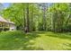View of the sprawling backyard with lush green lawn and mature trees surrounding the home at 4025 Cherrybrook Dr, Mint Hill, NC 28227