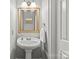 A stylish powder room features a pedestal sink, decorative mirror, and neutral color palette at 4025 Cherrybrook Dr, Mint Hill, NC 28227