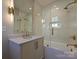 Stylish bathroom featuring a white vanity, gold fixtures, and a glass-enclosed shower-tub combo at 4121 Selwyn Walk Ct, Charlotte, NC 28209