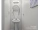 Neat powder room with a pedestal sink, round mirror, and clean fixtures, offering a functional and stylish space for guests at 5009 Granite Creek Ln, Charlotte, NC 28269