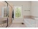 Bright bathroom featuring a tiled shower, soaking tub, and a large window for natural light at 5379 Roberta Meadows Ct, Concord, NC 28027