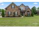 Charming brick home features a well-manicured lawn and lovely landscaping with mature trees and bushes at 5379 Roberta Meadows Ct, Concord, NC 28027