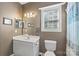 Neutral bathroom with a white vanity, toilet, framed mirror and window providing natural light at 6006 Casswell Cir, Matthews, NC 28104