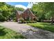 Traditional brick home boasting a long driveway, manicured landscaping, mature trees, and an attached two-car garage at 6006 Casswell Cir, Matthews, NC 28104