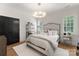 Serene bedroom showcasing a modern chandelier, plantation shutters, and a cozy bed, bathed in natural light at 6242 Creola Rd, Charlotte, NC 28270