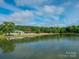 Scenic view of the community pond with calm water, surrounding trees, and a clubhouse in the background at 703 Bradberry Ln, Indian Trail, NC 28079