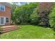 Backyard view featuring a brick home, wooden deck, and lush landscaping at 7301 Leharne Dr, Charlotte, NC 28270