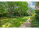 Manicured backyard with lush green lawn, mature trees, and a stepped retaining wall at 7301 Leharne Dr, Charlotte, NC 28270