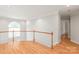 Upstairs hallway featuring wood floors, natural light, and white wood railing at 7301 Leharne Dr, Charlotte, NC 28270