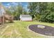 View of the backyard with a detached garage, fire pit, and small wood deck at 810 Maplewood Ave, Kannapolis, NC 28081