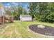 View of the backyard with a detached garage, fire pit, and small wood deck at 810 Maplewood Ave, Kannapolis, NC 28081