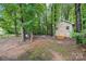Backyard shed nestled among trees with a small wooden ramp, providing ample storage space at 8618 Sam Dee Rd, Charlotte, NC 28215