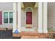 Inviting covered front entrance with brick steps, white pillars, dark red front door, and 'hello' welcome mat at 8618 Sam Dee Rd, Charlotte, NC 28215